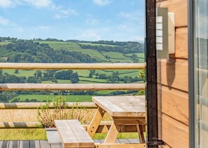 Eine Holterrasse mit Picknicktischen mit Blick auf eine ländliche Landschaft.