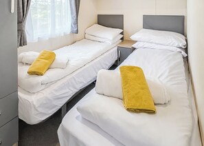 Ein Hotelzimmer mit zwei Einzelbetten, jeweils mit einer weißen Matratze und einem gelben Handtuch.