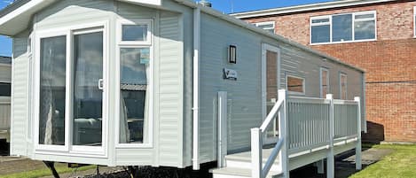 A mobile home with a front porch and a staircase leading to the entrance.