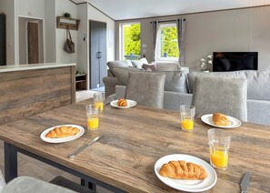 Un comedor con una mesa de madera preparada para el desayuno, incluyendo croissants y zumo de naranja.