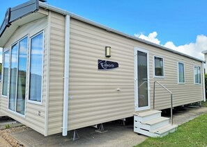 Une maison mobile avec une enseigne indiquant « Lulworth » et un escalier menant à l’entrée.