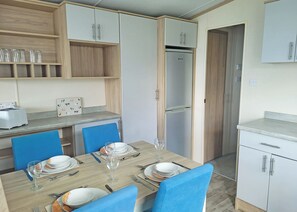 A dining area with a table set for four, blue chairs, and a refrigerator in the background. - 1 bedroom accommodation in Dorchester (Dorchester)