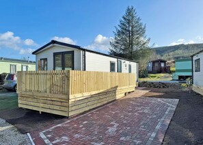 A mobile home with a wooden deck, a brick patio, and a clear sky. - 3 bedroom accommodation in Ettrick Valley, Nr Hawick (Ettrick Valley, Nr Hawick)