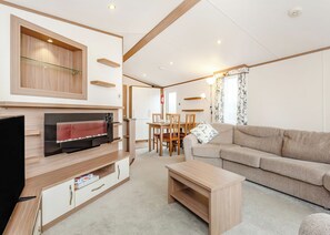 A modern living room with a flat-screen TV, wooden furniture, a sofa, and a dining area. - Modern two-bedroom holiday home. (Fort Augustus)