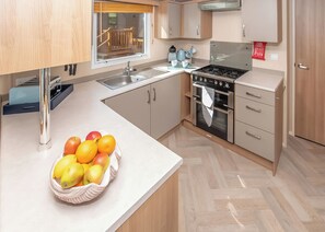 A modern kitchen with a built-in oven, a sink, and a fruit bowl on the counter. - 2 bedroom accommodation in Budleigh Salterton (Budleigh Salterton)