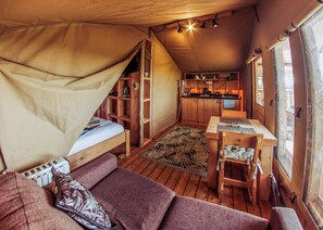 Ein gemütliches Interieur mit einem Bett, einer kleinen Küchenzeile und einem Essbereich.