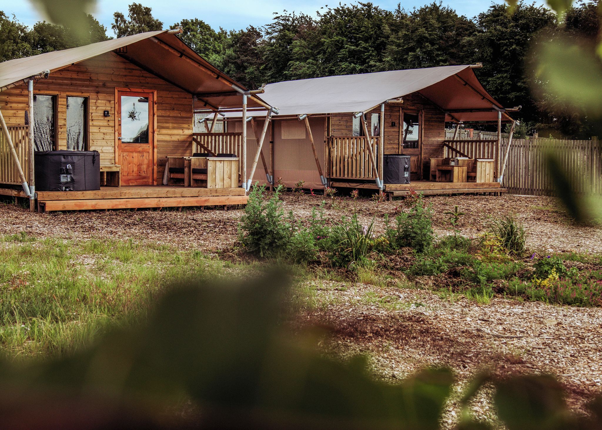 A wooden cabin with a porch, a covered outdoor seating area, and a small deck.
