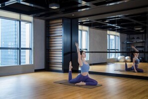A yoga studio with a large mirror, wooden flooring, and a city view. - Oakwood Residence Foshan (Foshan)