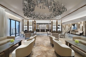 A modern hotel lobby with a central seating area, a reception desk, and a large window offering a city view. - Oakwood Residence Foshan (Foshan)