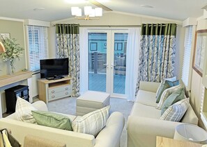 Een woonkamer met een televisie, bank en een schuifdeur naar een buitenruimte.
