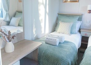 A neatly arranged bedroom with a bed, bedside table, and a mirror. - Premium 2 bedroom holiday home with hot tub (Bassenthwaite, near Keswick)