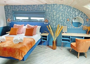 A bedroom with a bed, bedside table, chair, desk, mirror, and a vase with dried plants. - Glamping Pod with hot tub - Pet Friendly (Bassenthwaite, near Keswick)