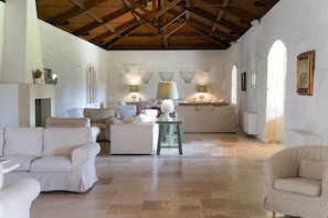 A spacious room with a high ceiling, white walls, and a tiled floor. There are several pieces of furniture including sofas and a table. - Masseria Lilei (Lizzanello)