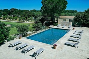 A rectangular swimming pool with lounge chairs and a stone building in the background. - Masseria Lilei (Lizzanello)