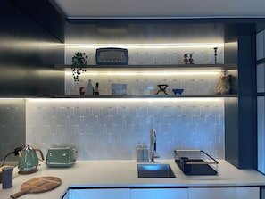 A modern kitchen with a white countertop, a built-in radio, and a variety of kitchen utensils and decorations. - Stylish 2BDR Collingwood Apartment with Parking (Collingwood)