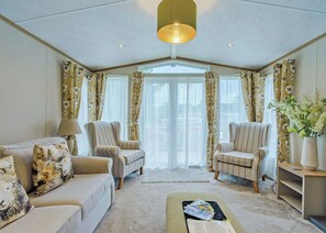 A living room with a sofa, two armchairs, a coffee table, and a bookshelf. - Superior Hot Tub 2 bed Holiday Home sleeps 4 Pet (Bassenthwaite, near Keswick)