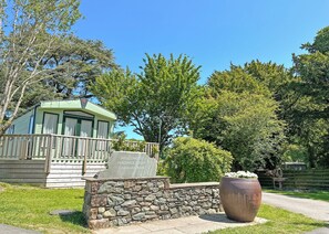 A caravan park entrance with a stone wall, a wooden sign, and a large planter. - Superior Hot Tub 2 bed Holiday Home sleeps 4 Pet (Bassenthwaite, near Keswick)