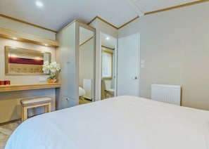 A hotel room with a bed, a bedside table, a mirror, a radiator, and a door leading to a bathroom. - Superior Hot Tub 2 bed Holiday Home sleeps 4 Pet (Bassenthwaite, near Keswick)