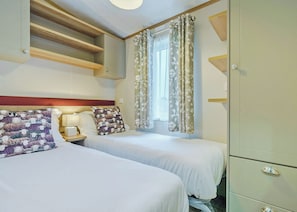 A hotel room with two beds, a nightstand, a lamp, a wardrobe, and a window with curtains. - Superior Hot Tub 2 bed Holiday Home sleeps 4 Pet (Bassenthwaite, near Keswick)