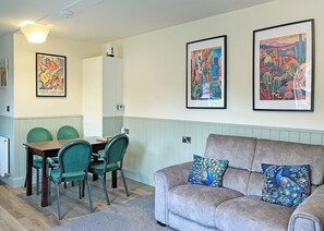 A living room with a grey sofa, two green chairs, a wooden table, and two framed artworks on the wall. - Comfortable and well-equipped two bedroom lodge, ideal for couples or families. (Pickering)