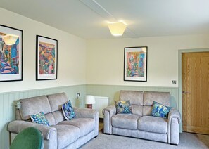 A living room with two grey sofas, a radiator, and three framed artworks on the wall. - Comfortable and well-equipped two bedroom lodge, ideal for couples or families. (Pickering)