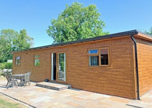 A wooden cabin with a patio, a door, and windows. - Comfortable and well-equipped two bedroom lodge, ideal for couples or families. (Pickering)