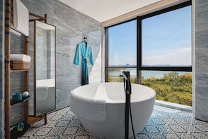 A modern bathroom with a freestanding bathtub, a large mirror, and a view of a body of water through a large window. - Hotel Indigo Suzhou Jinji Lake (Suzhou)