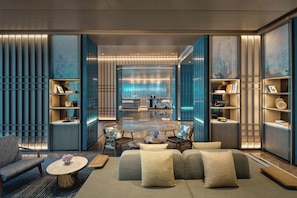A modern hotel lobby with a central seating area, bookshelves, and a large window with a cityscape view. - Hotel Indigo Suzhou Jinji Lake (Suzhou)