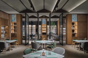 A modern restaurant with high ceilings, wooden paneling, and a mix of seating arrangements including tables and chairs. - Hotel Indigo Suzhou Jinji Lake (Suzhou)