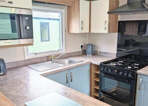A compact kitchen with a stove, oven, microwave, and sink. - Tweed Spa + - 2 Bedroom (Pet Friendly) (Coldstream)