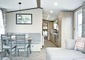 A modern, compact living space with a dining area, kitchenette, and a sofa. - Spa Luxe - 2 Bedroom (Pet Friendly) (Coldstream)