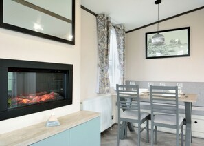 A modern kitchen with a built-in fireplace, a dining table with chairs, and a framed picture on the wall. - Spa Luxe - 2 Bedroom (Pet Friendly) (Coldstream)