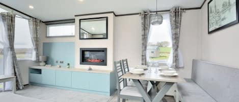 A modern kitchen with a built-in stove, a dining area with a table and chairs, and a large window with curtains.