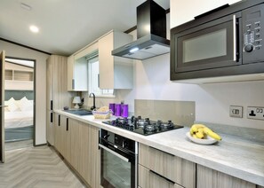 A modern kitchen with a built-in microwave, gas stove, and stainless steel appliances. - Spa Luxe - 2 Bedroom (Pet Friendly) (Coldstream)