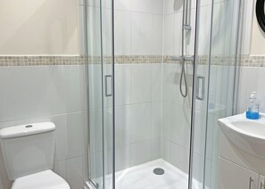A modern bathroom with a glass-enclosed shower, a white toilet, and a sink with a soap dispenser. - Comfortable and well-equipped two bedroom lodge, ideal for couples or families. (Pickering)