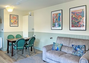 A living room with a grey sofa, two green chairs, a wooden table, and two framed artworks on the wall. - Comfortable and well-equipped two bedroom lodge, ideal for couples or families. (Pickering)