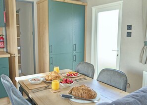 A breakfast setting with a table, chairs, and a variety of food items including bread, fruit, and a croissant. - Luxury 3 Bedroom Holiday Home (Bassenthwaite, near Keswick)