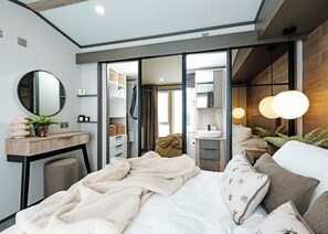 Ein modernes Schlafzimmer mit einem großen Bett, Nachttischen, einem Spiegel und einem Kleiderschrank.