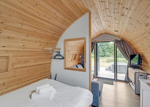 A cozy room with a bed, a mirror, a television, and a view of the outdoors. - Aura Spa + Glamping Pod (Pet Friendly) (Coldstream)
