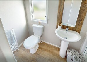 Ein kleines Badezimmer mit Toilette, Waschbecken und Fenster.