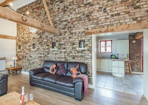 Ein großzügiger Wohnbereich mit Backsteinwand, Ledersofa und Esstisch aus Holz.