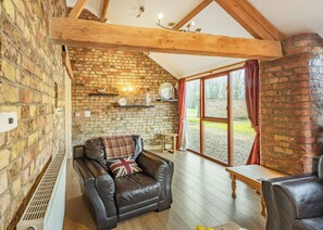 A cozy room with a brick wall, a leather sofa, a wooden table, and a large window. - 1 bedroom accommodation in Beverley (Beverley)