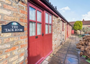 A brick building with a red door and a sign reading 'The Tack Room'. - 1 bedroom accommodation in Beverley (Beverley)