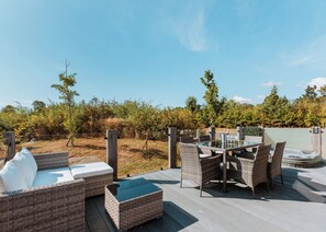 An outdoor patio with wicker furniture, a hot tub, and a view of a vineyard. - Cherry Lodge VIP Hot Tub and Pet Friendly (Bridgnorth)