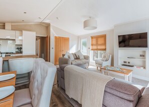 A modern living room with a sofa, armchairs, a coffee table, and a television. - Cherry Lodge VIP Hot Tub and Pet Friendly (Bridgnorth)