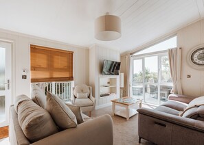 A spacious living room with a large window, a television, and a clock on the wall. - Cherry Lodge VIP Hot Tub and Pet Friendly (Bridgnorth)