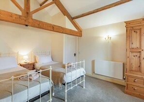 A bedroom with two beds, a wooden wardrobe, a radiator, and a wall-mounted light fixture. - 1 bedroom accommodation in Beverley (Beverley)