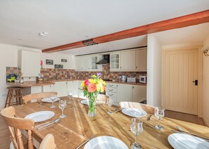 A dining area with a wooden table set for six, surrounded by chairs, with a vase of flowers in the center. - 1 bedroom accommodation in Beverley (Beverley)