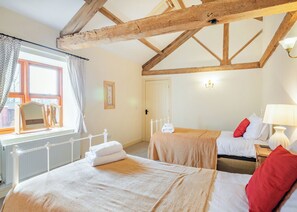 A room with two beds, a window with curtains, a radiator, and a wooden ceiling beam. - 1 bedroom accommodation in Beverley (Beverley)