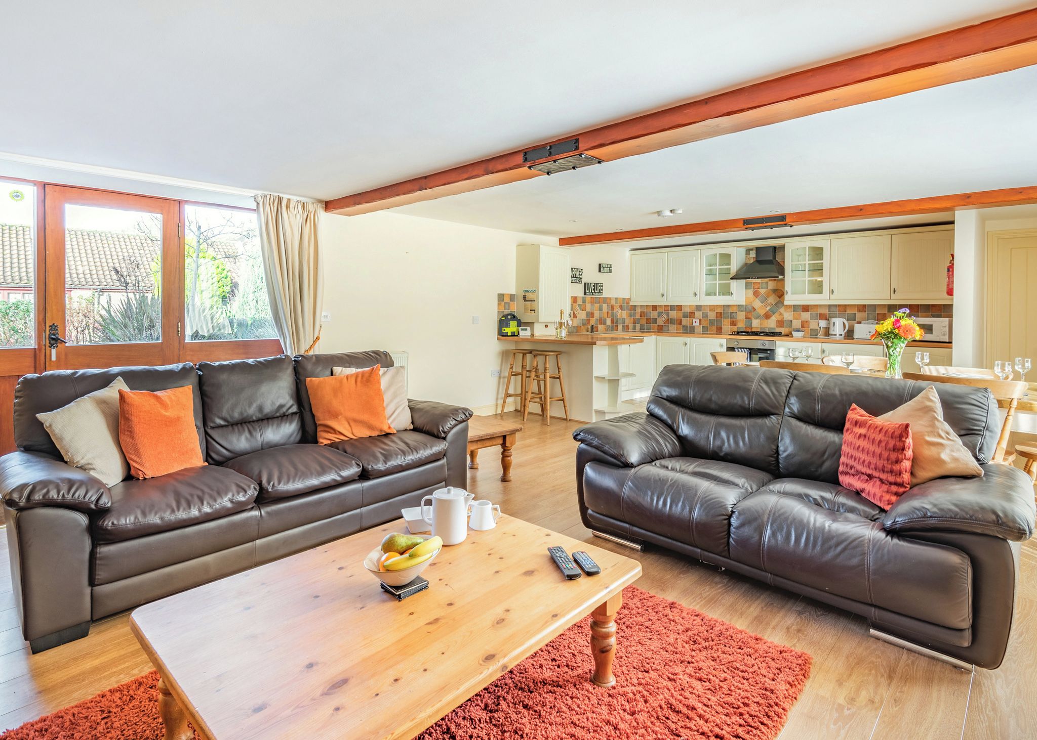 A modern living room with two leather sofas, a wooden coffee table, and a kitchen in the background.